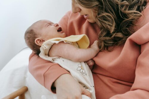 unrecognizable mother with crying baby in arms